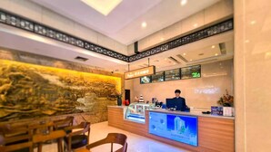 A hotel reception area with a receptionist, a digital display, and a traditional mural. - Hangzhou Haiwaihai Communication Hotel (Hangzhou)