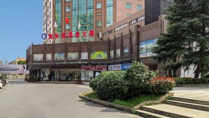 A multi-story hotel with a prominent sign in a foreign language, a covered entrance, and a parking lot in front. - Hangzhou Haiwaihai Communication Hotel (Hangzhou)