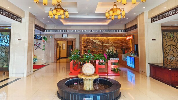 A lobby with chandeliers, a reception desk, a fountain, and a wall with traditional artwork. - Hangzhou Haiwaihai Communication Hotel (Hangzhou)