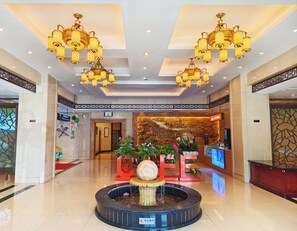 A lobby with chandeliers, a reception desk, a fountain, and a wall with traditional artwork. - Hangzhou Haiwaihai Communication Hotel (Hangzhou)
