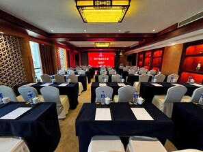 Un salón de conferencias con mesas dispuestas para una reunión, equipado con botellas de agua y tarjetas de identificación.