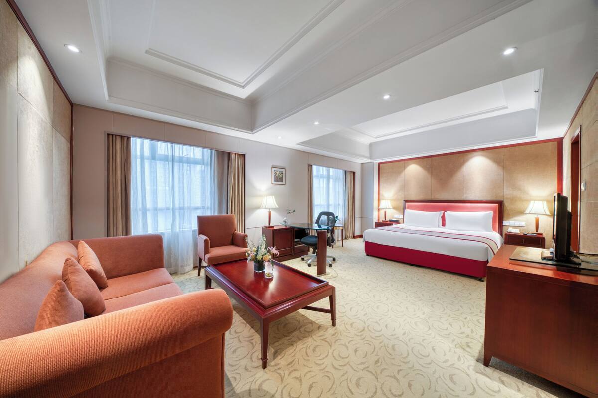 A hotel room with a bed, a sofa, a desk, and a chair.