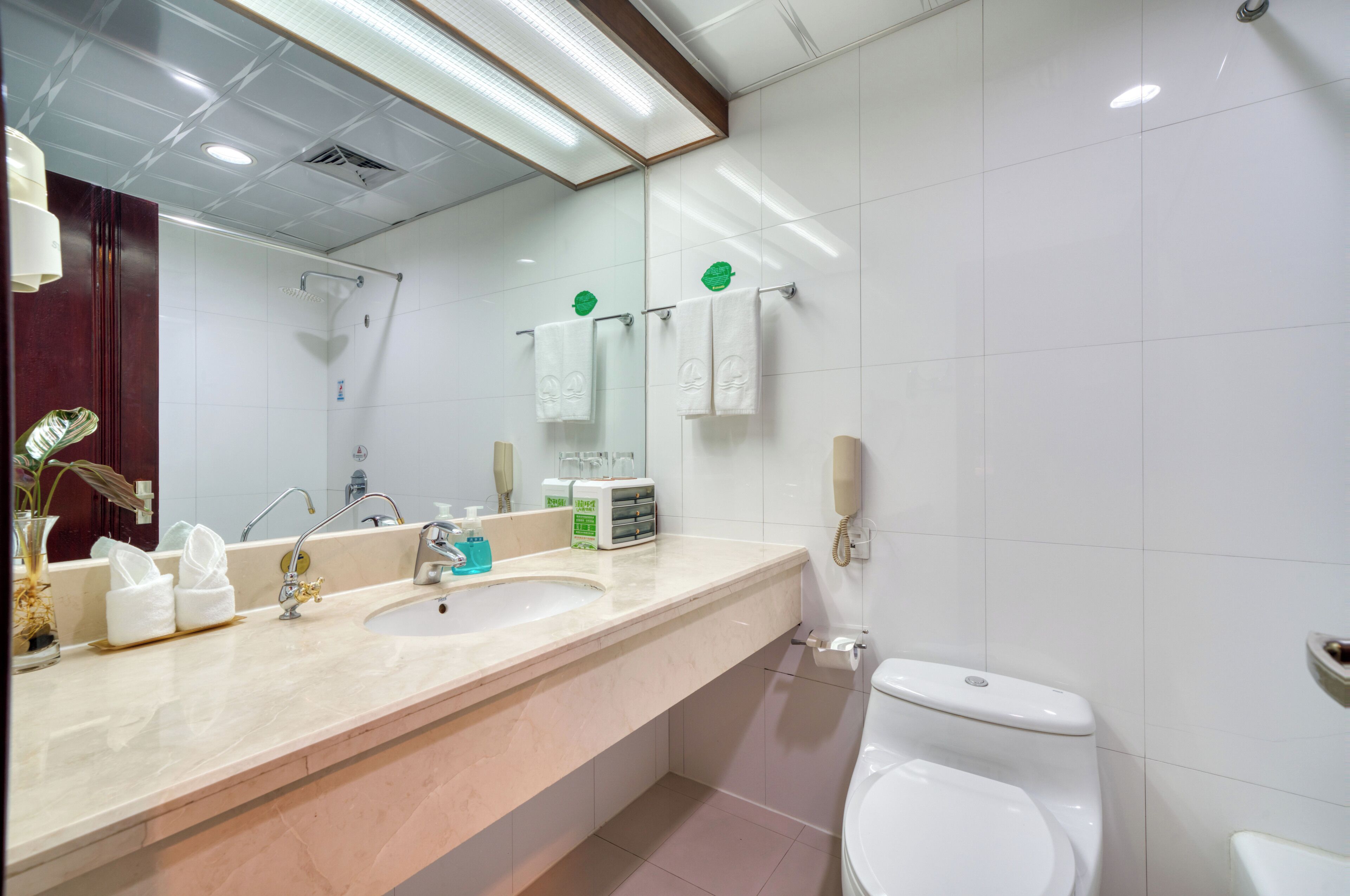 Um banheiro moderno com um espelho grande, duas pias, um vaso sanitário e um chuveiro.
