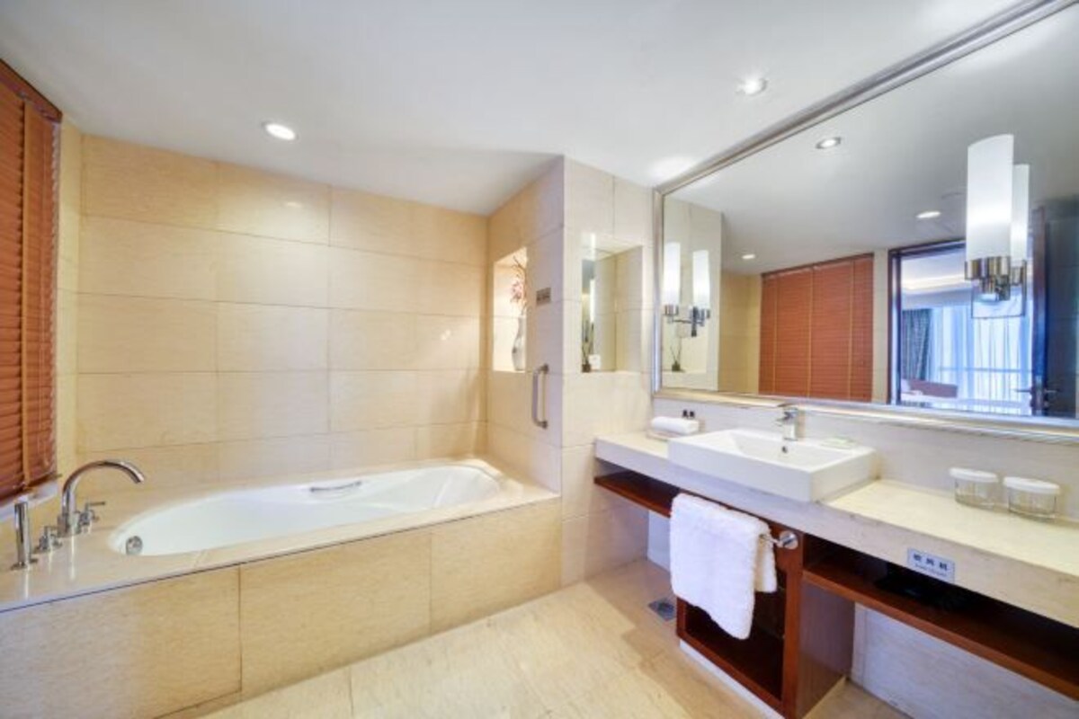 A modern bathroom with a large bathtub, a vanity with a mirror, and a sink.