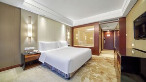 A hotel room with a large bed, a desk with a lamp, a TV, and a walk-in closet. - Hangzhou Haiwaihai Hotel (Hangzhou)