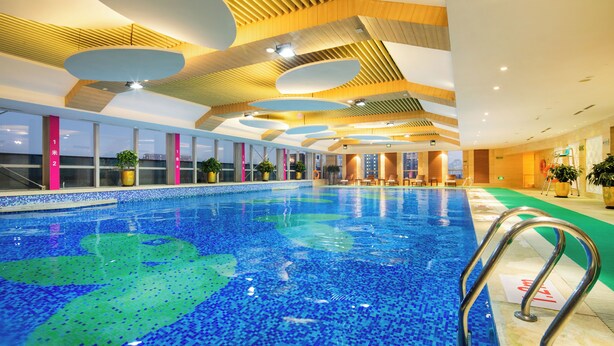 An indoor swimming pool with a tiled floor and a wooden ceiling with recessed lighting. - Hangzhou Haiwaihai Hotel (Hangzhou)
