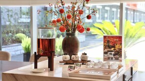 A table with a vase of flowers, a teapot, and a teacup set. - Haiwaihai Baina Hotel (Hangzhou)