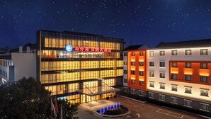 A modern hotel with a prominent sign, a well-lit entrance, and a fountain in the courtyard. - Haiwaihai Baina Hotel (Hangzhou)