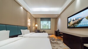 A hotel room with two beds, a desk, a TV, and a window. - Haiwaihai Baina Hotel (Hangzhou)