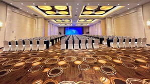 A conference room with rows of chairs, a stage, and a large screen. - Haiwaihai Baina Hotel (Hangzhou)