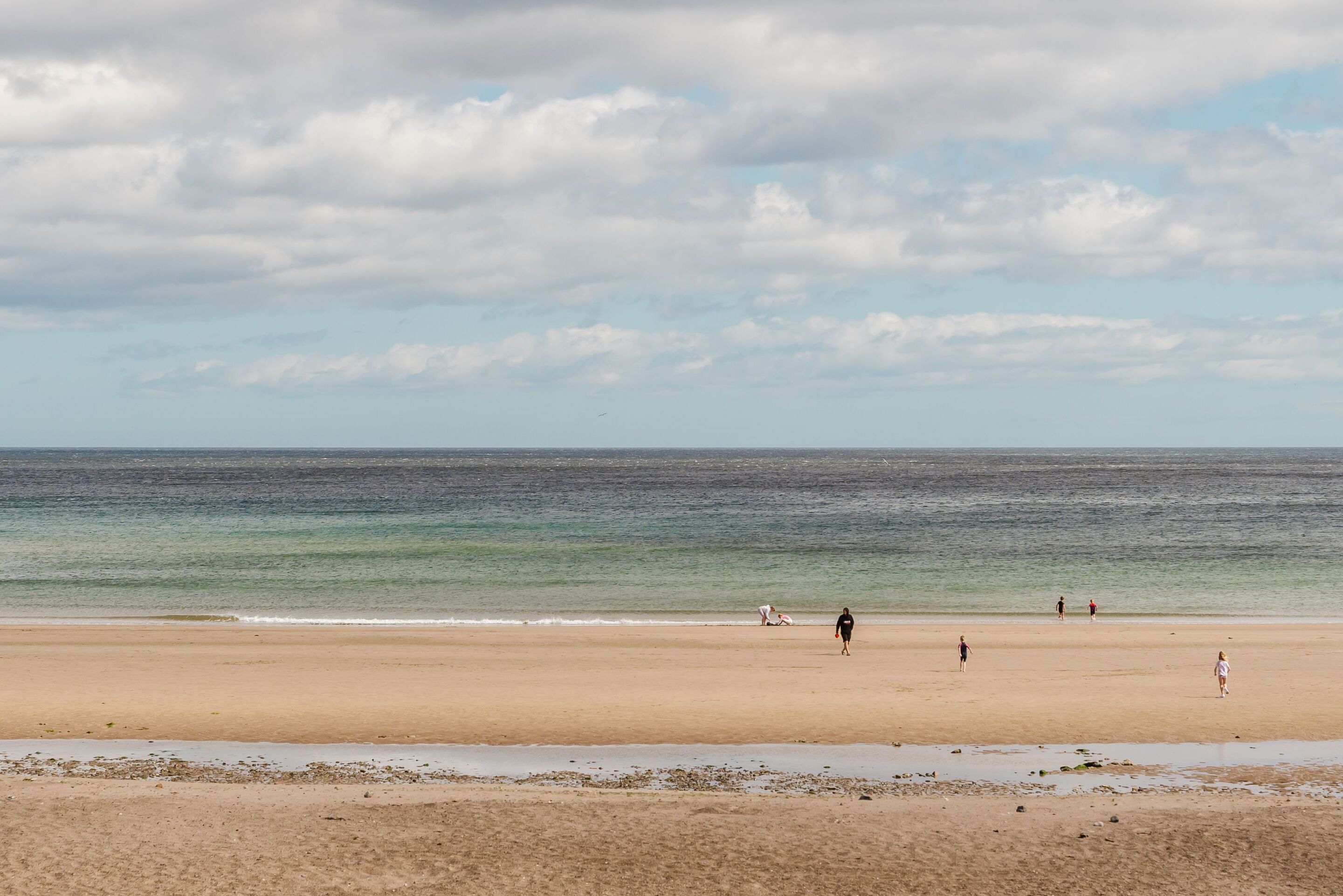Une plage avec un rivage sablonneux et une mer calme sous un ciel nuageux.