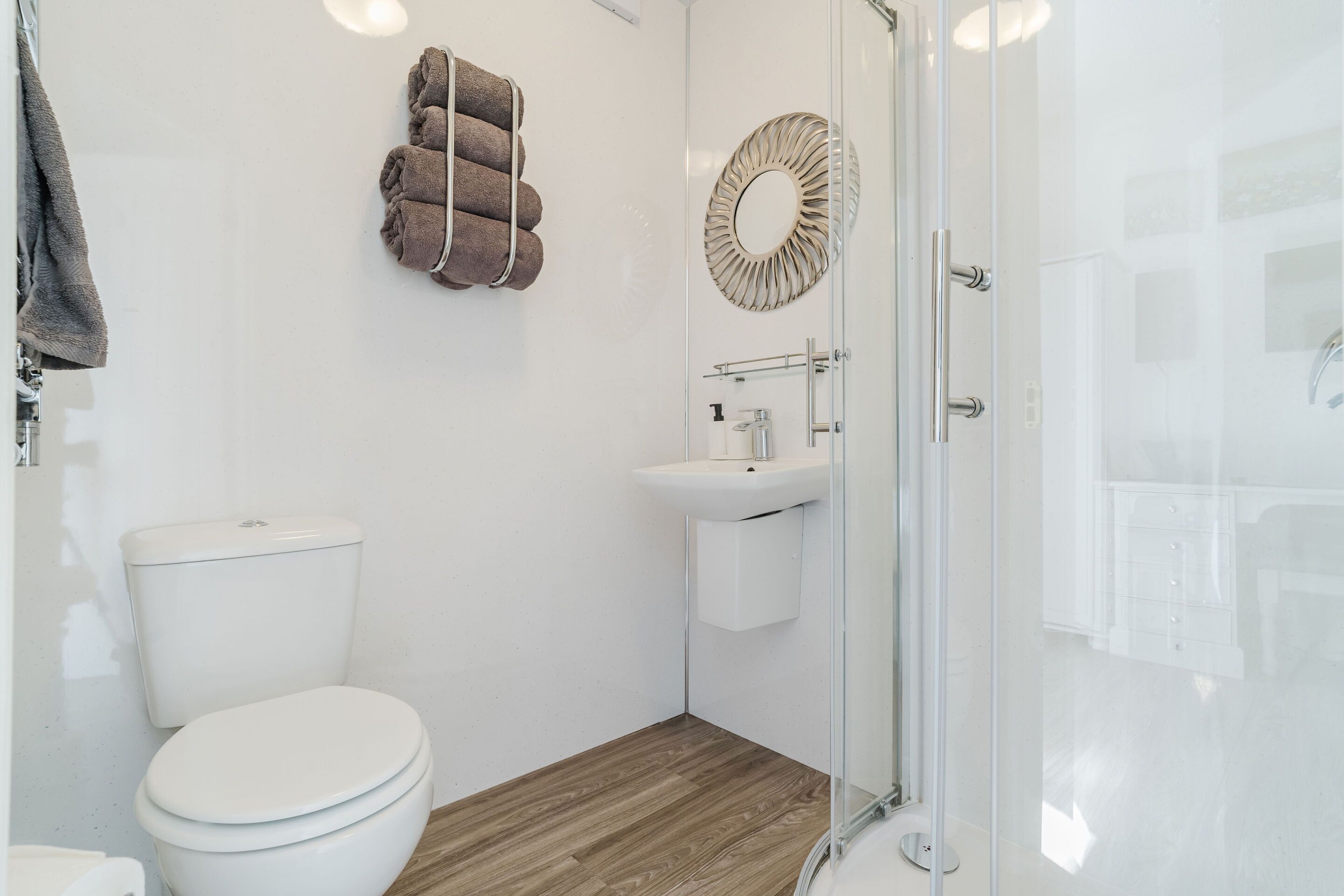 Un baño moderno con inodoro, lavamanos y cabina de ducha de vidrio.