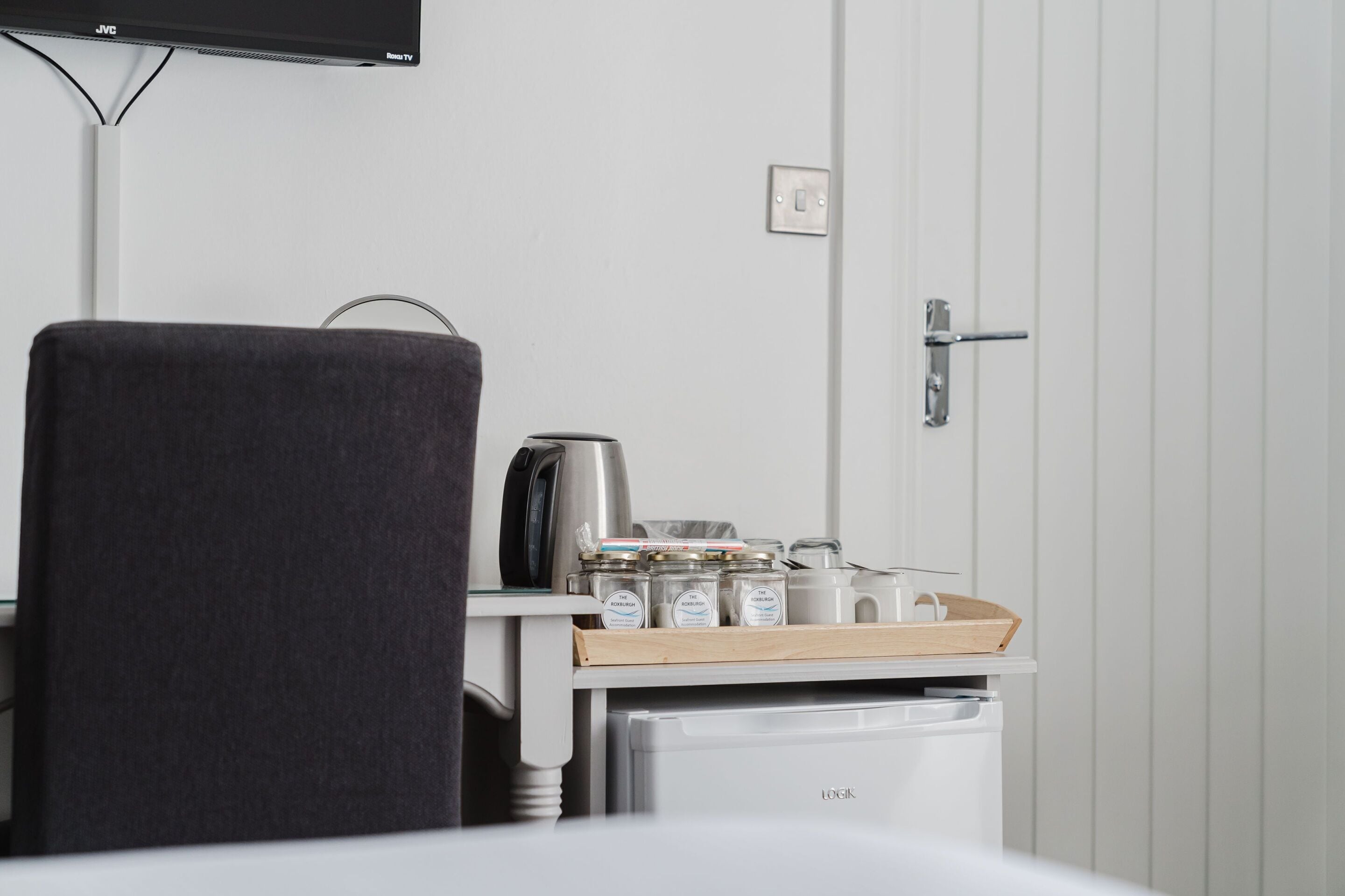Une chambre d’hôtel avec un lit, une petite kitchenette, une télévision et une porte.