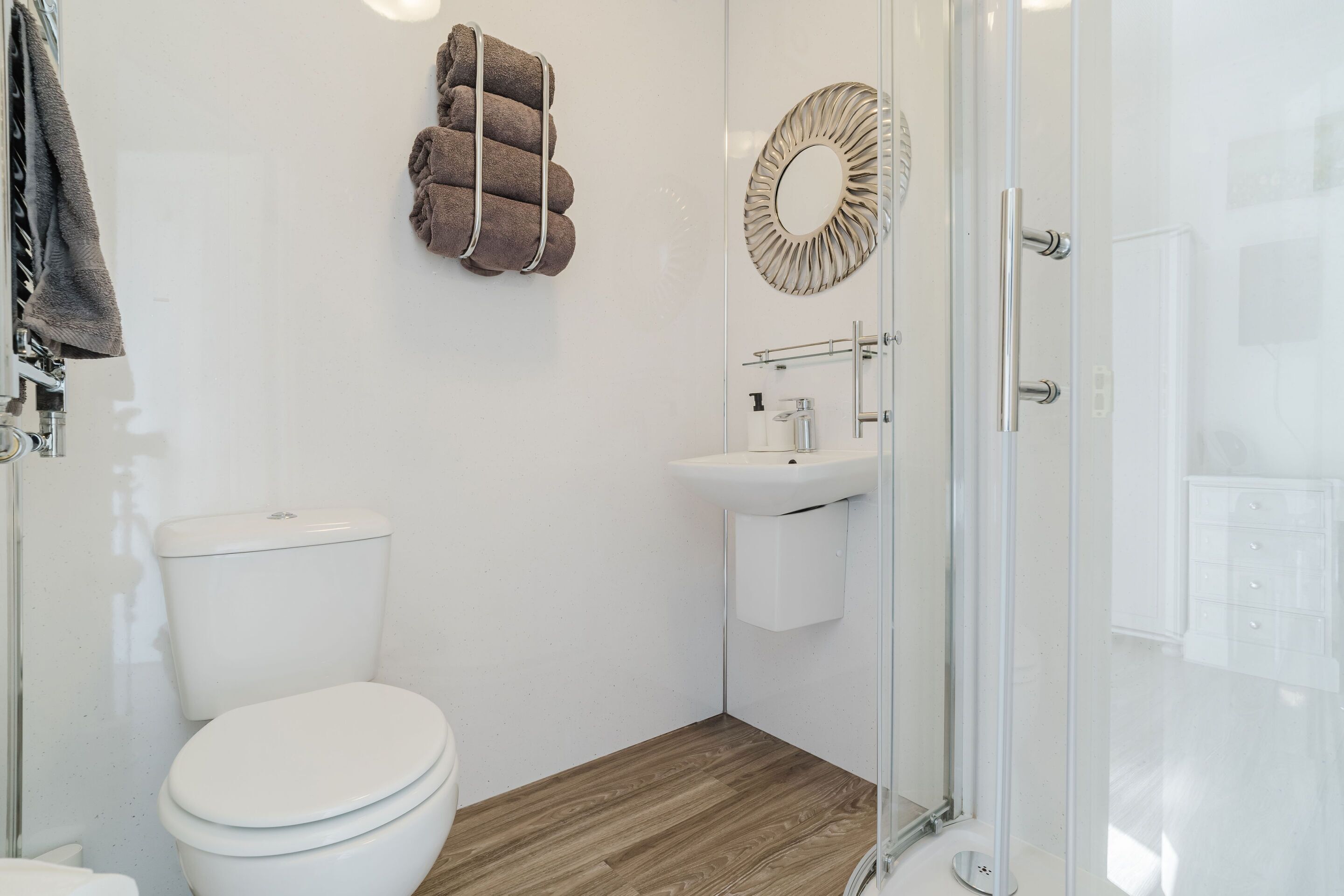 Un baño moderno con inodoro, lavamanos y cabina de ducha de vidrio.
