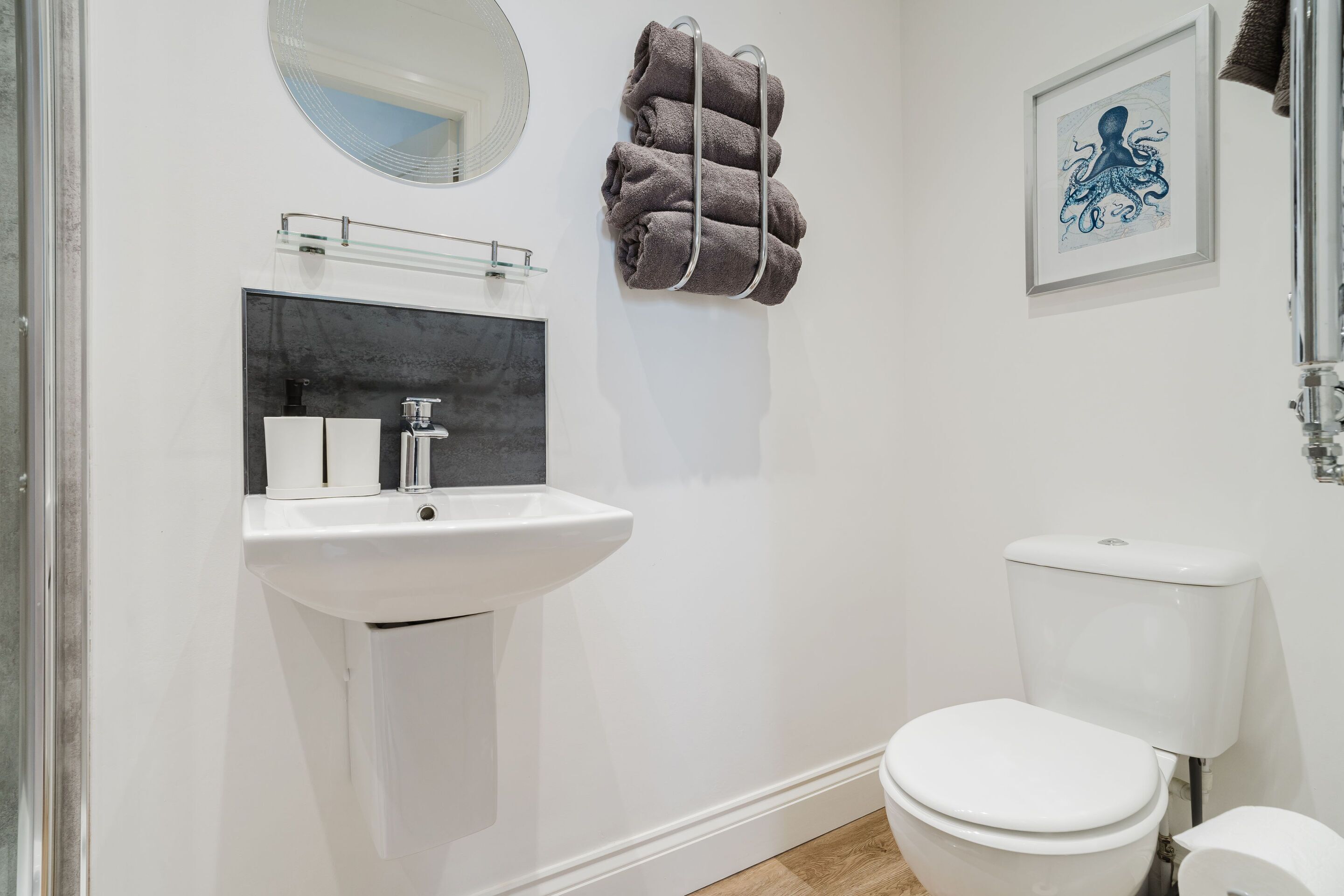 Un baño moderno con un lavamanos blanco, un inodoro y un perchero para toallas.