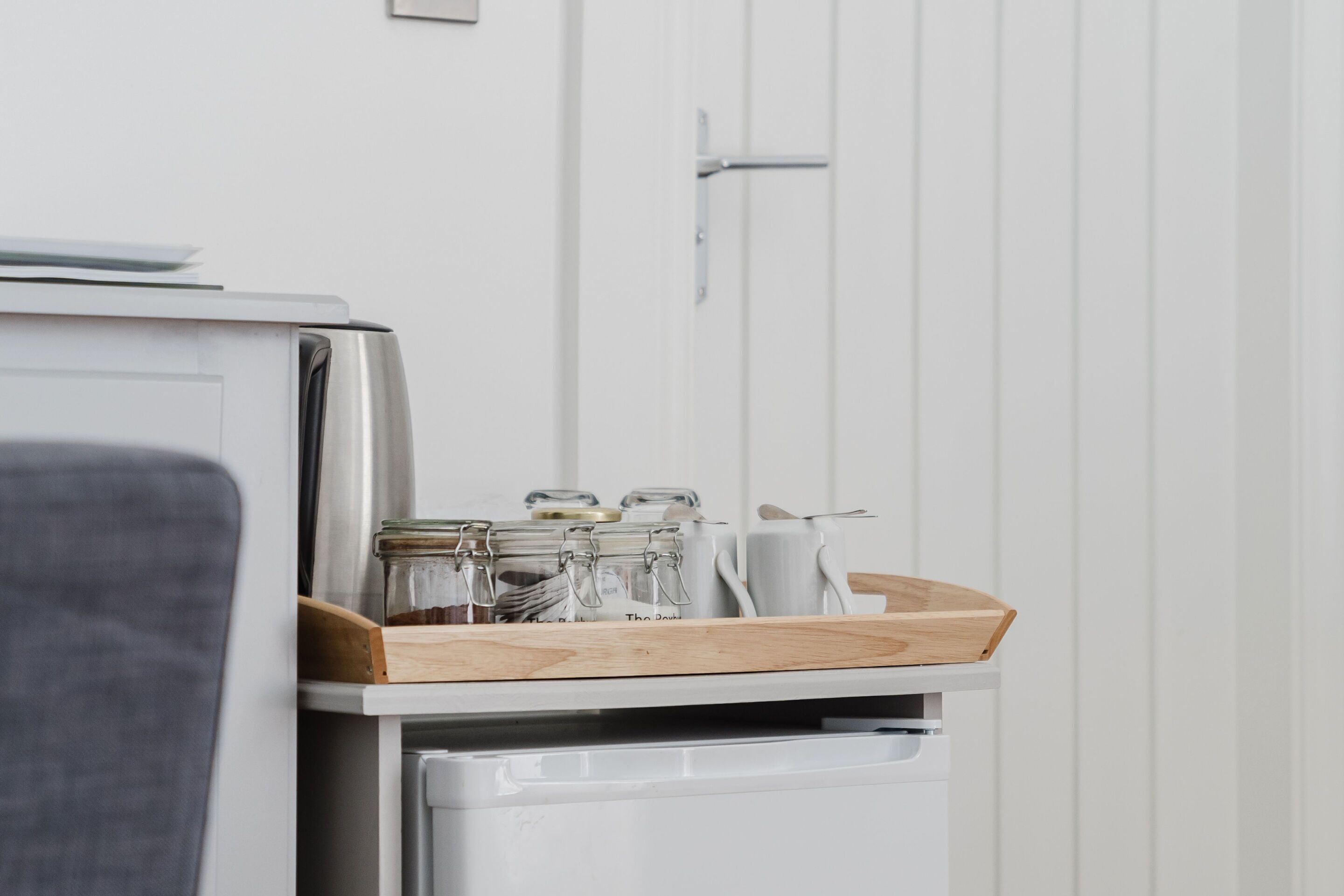 A kitchen area with a white refrigerator, a wooden cutting board, and glass jars on the door.