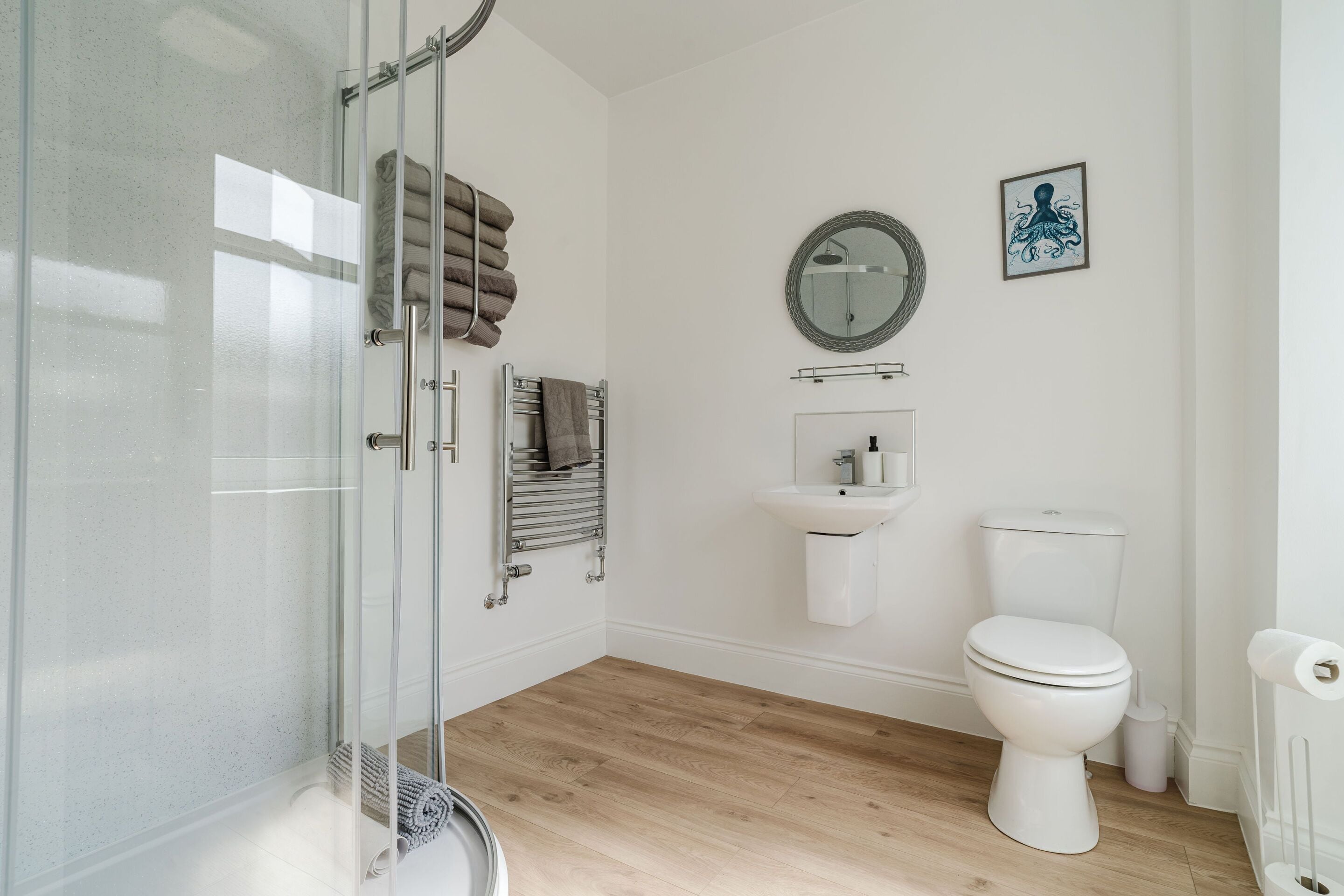 A modern bathroom with a glass shower enclosure, a white sink, and a toilet.