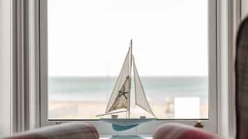 Un velero modelo sobre un alféizar con vista al mar.