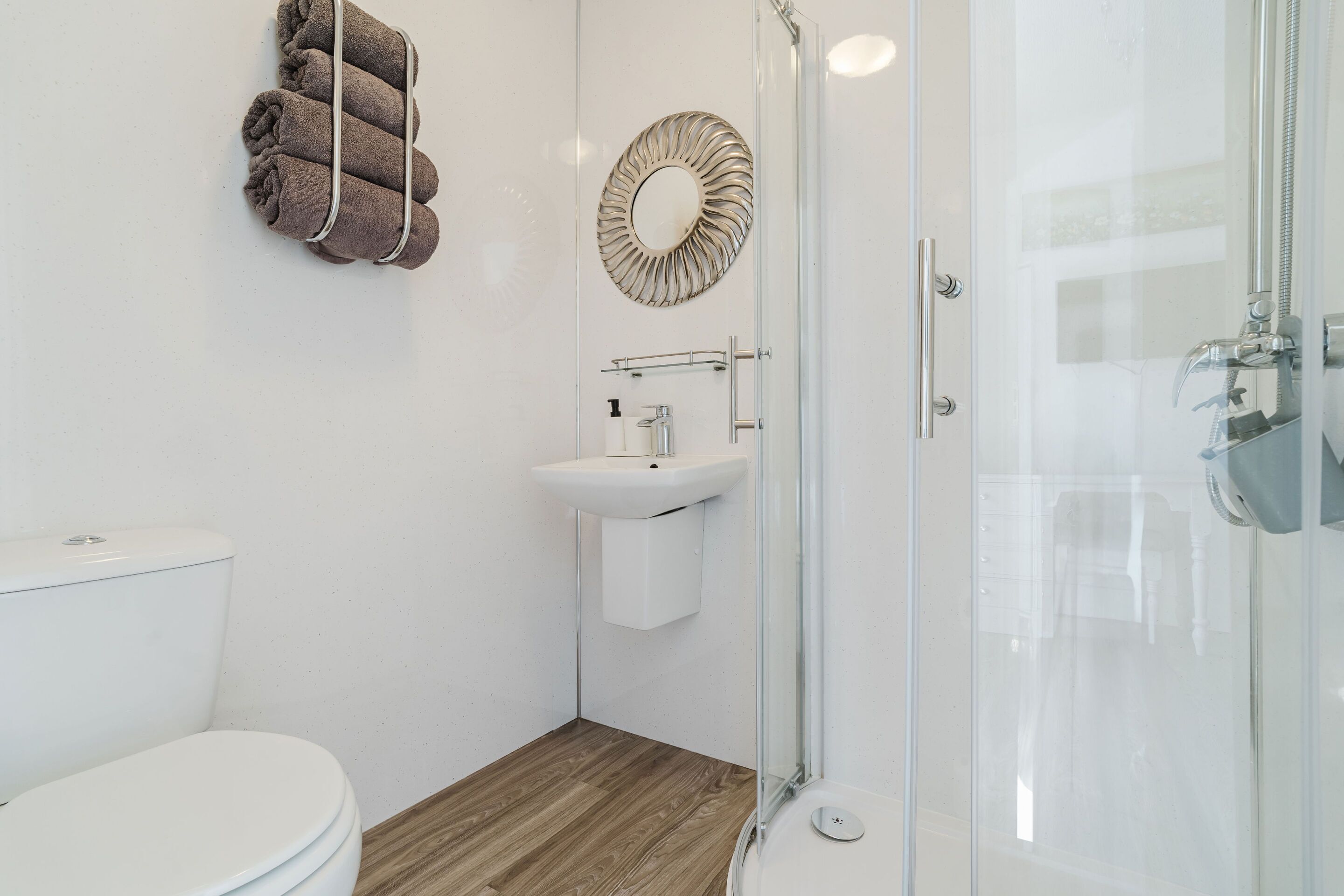 A bathroom with a toilet, sink, and glass shower enclosure.