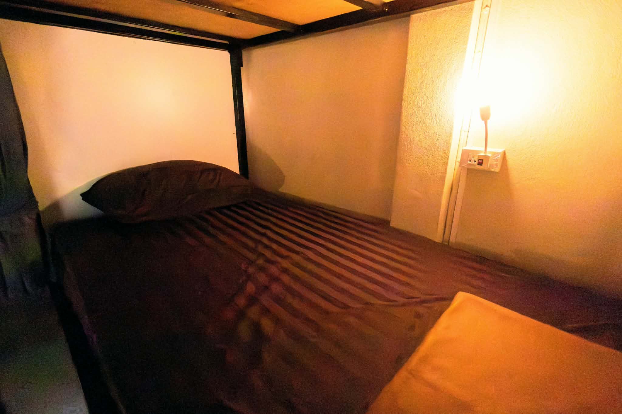 A single bed with a headboard, a bedside table, and a wall-mounted light fixture.