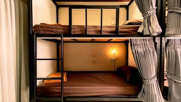 A bunk bed room with a single bed on the bottom bunk and a wall-mounted light.
