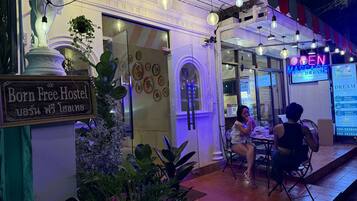 A hostel with a sign reading 'Born Free Hostel' and a neon sign for 'Open Massage'.