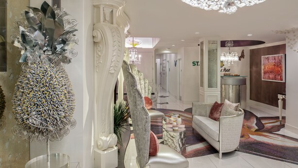 Um interior moderno com um sofá branco, uma escultura metálica decorativa e um candelabro.