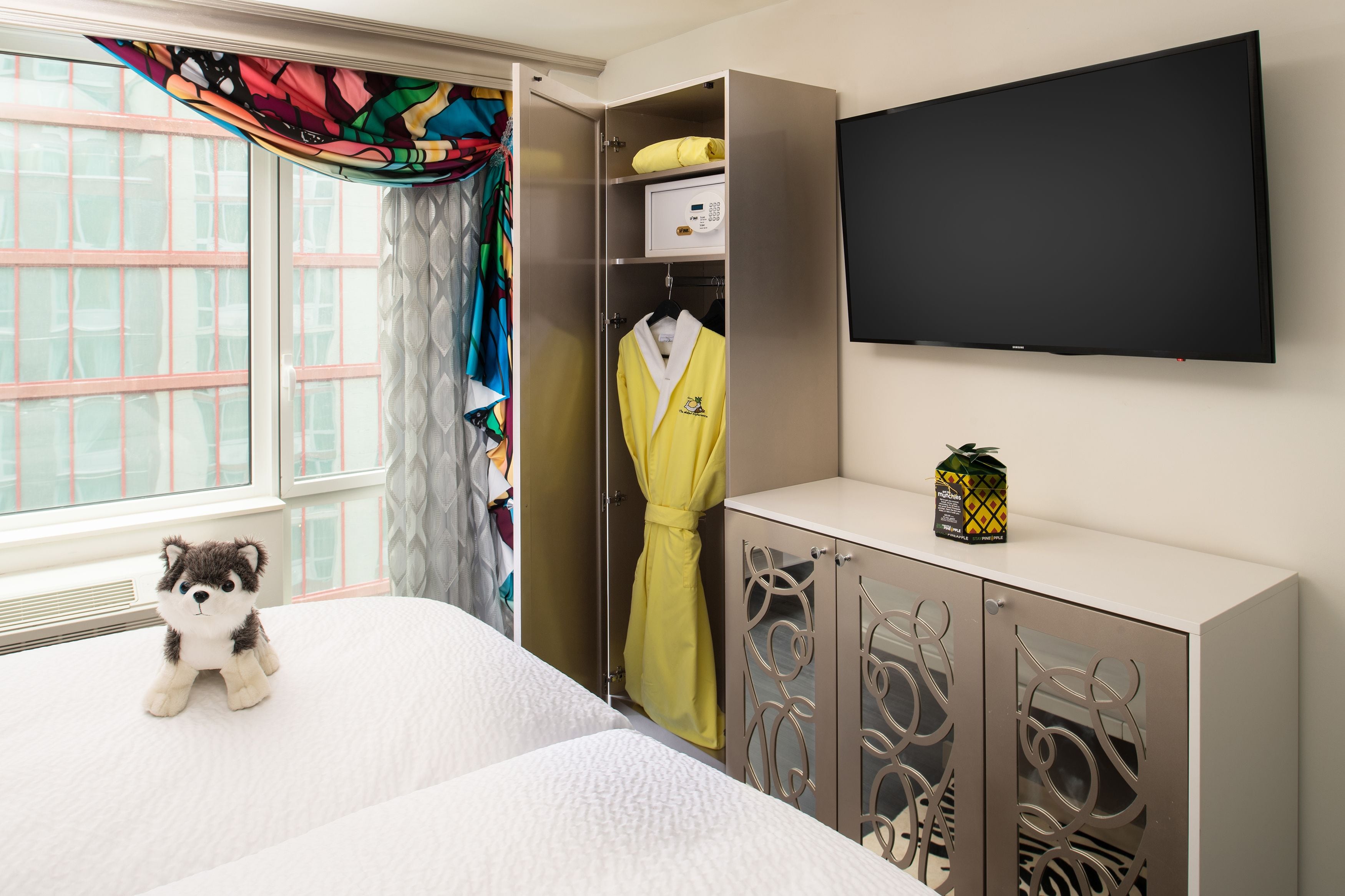 Ein Hotelzimmer mit Bett, Kleiderschrank, Fernseher und einem fenster mit Vorhängen.