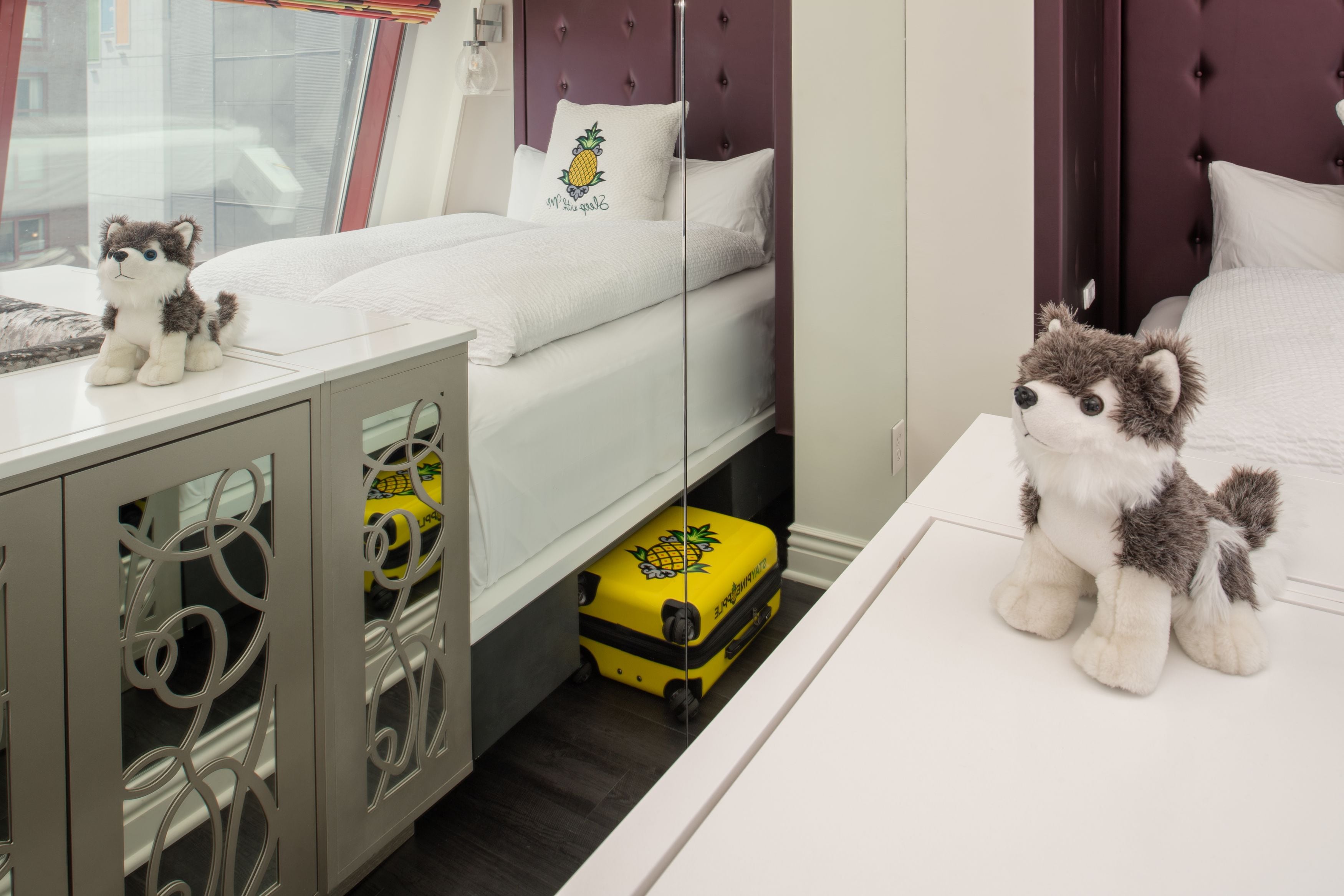 Una habitación de hotel con cama, tocador, espejo y maleta.