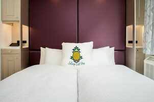 A neatly made bed with a pillow featuring a pineapple design and the text "Sleep with Me".