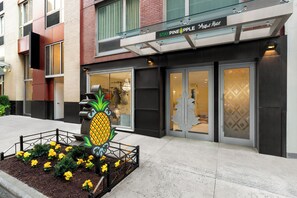 A hotel entrance with a pineapple sculpture, a glass balcony, and a sign reading 'Stay Pineapple.' - Staypineapple, An Artful Hotel, Midtown (New York)