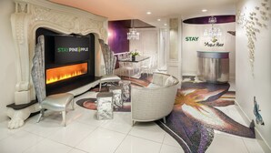 Um hall moderno de hotel com lareira, televisão e área de refeições.