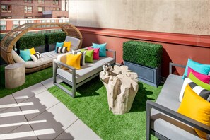 A rooftop terrace with a wicker sofa, a metal table, and a decorative tree stump. - Staypineapple, An Artful Hotel, Midtown (New York)