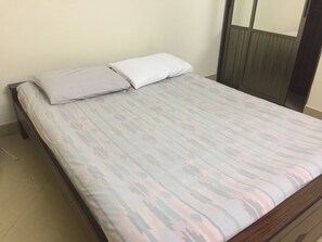 Una cama individual con una colcha estampada y dos almohadas, un cabecero de madera y un espejo en la pared.