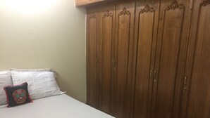 A bedroom with a bed, a wardrobe, and a pillow with a skull design. - Latif villa (Dhaka)