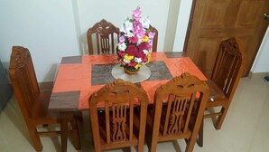 A dining table with a floral centerpiece, surrounded by wooden chairs. - Latif villa (Dhaka)