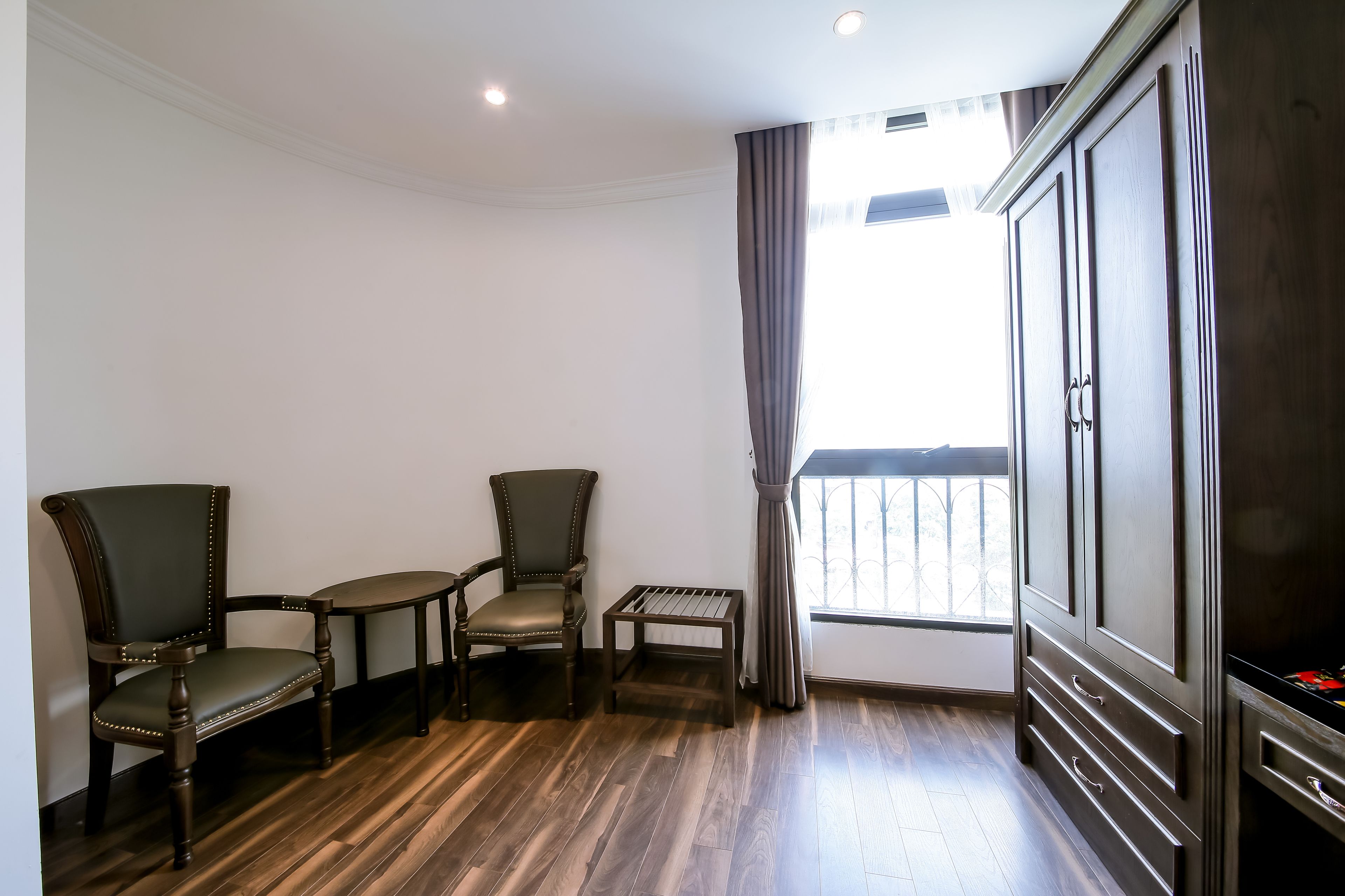 A room with two dark wooden chairs, a small table, and a cabinet with drawers.