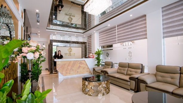 A hotel reception area with a reception desk, a chandelier, a sofa, and a coffee table. - Louisland Hotel (Hanoi)