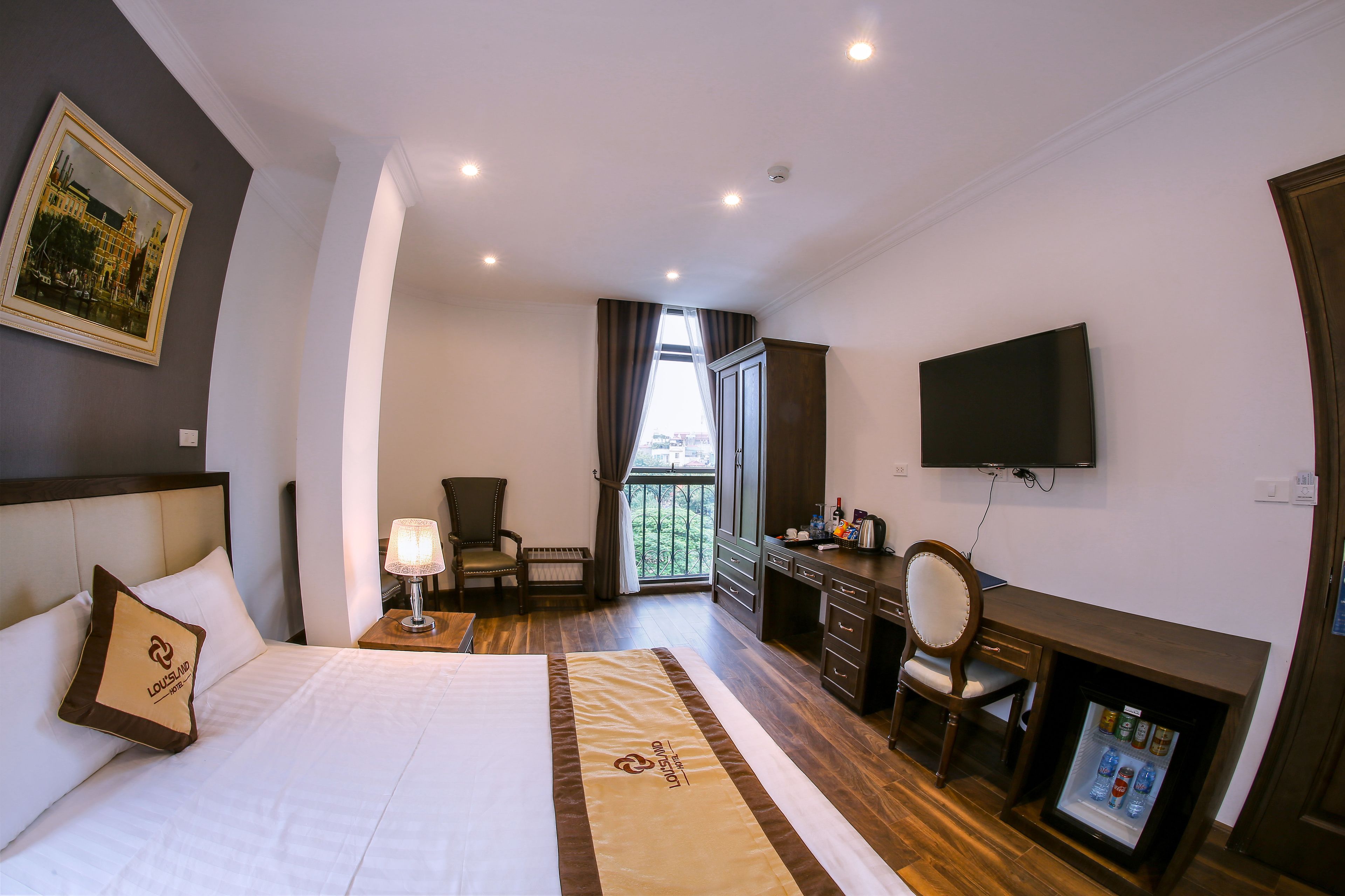 A hotel room with a bed, a desk, a TV, a chair, and a minibar.