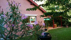 A pink house with a window, a garden with grass and plants, and a red structure. - Villa Seignemartin (Lyon)