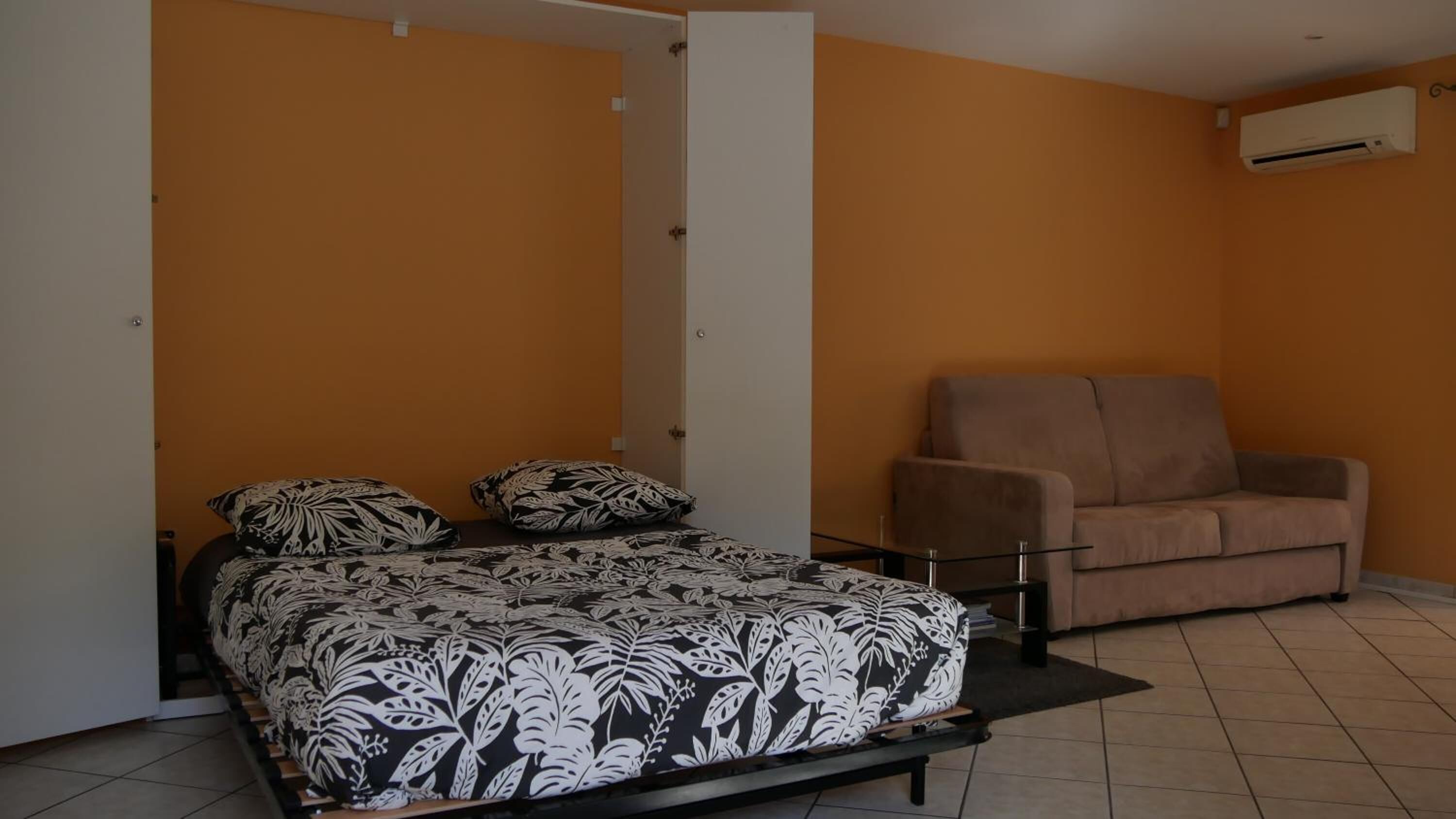 Un dormitorio con cama, sofá y un equipo de aire acondicionado.