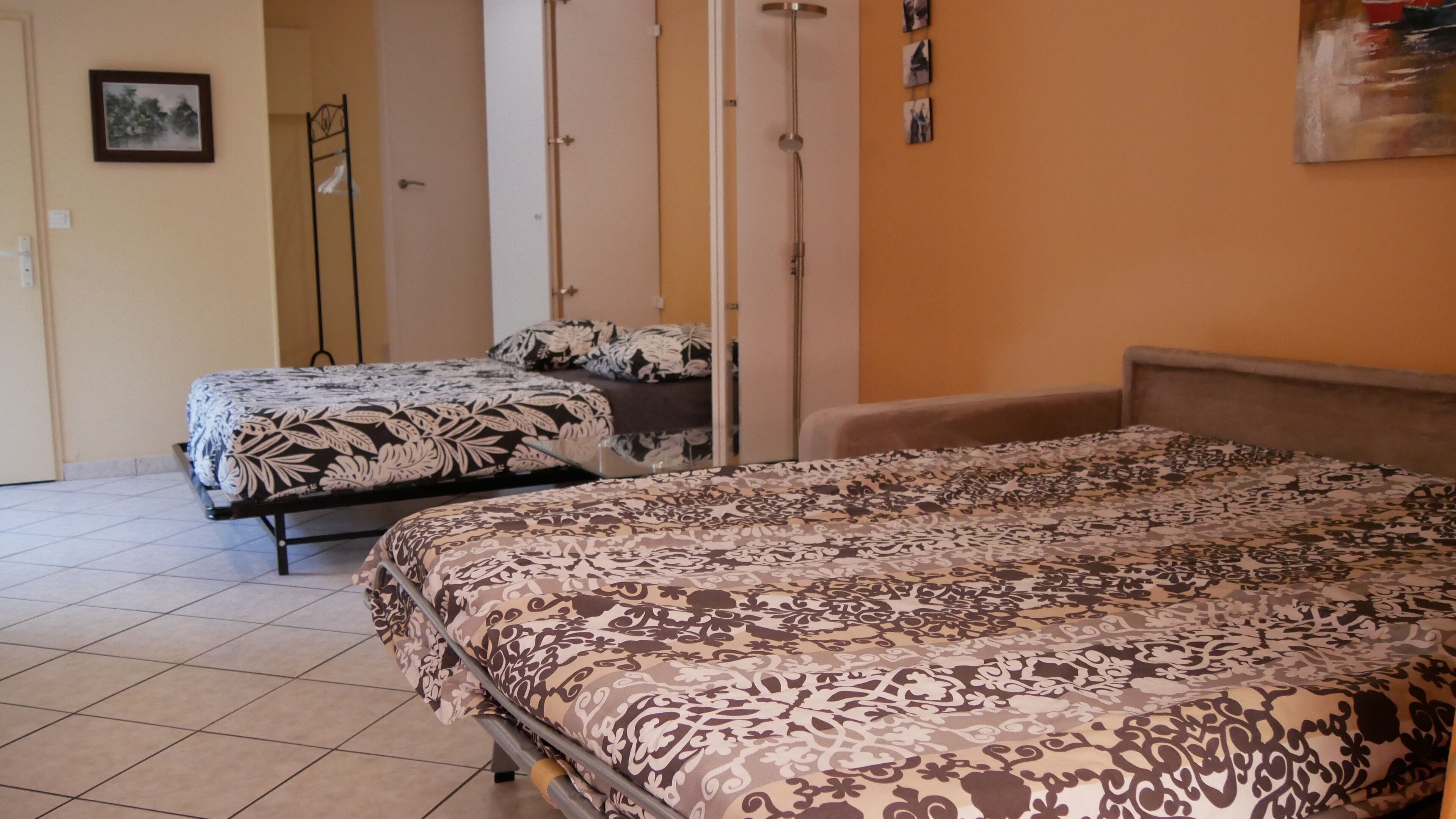 A hotel room with two beds, a wardrobe, and a shower.