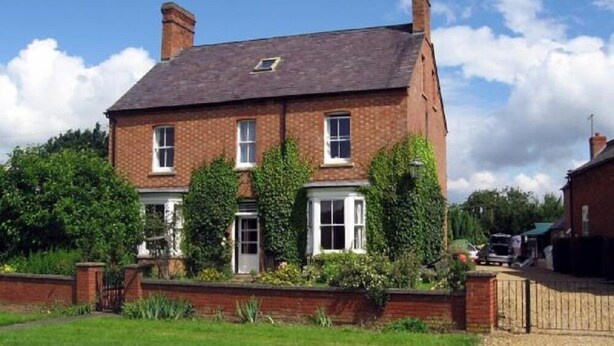 A two-story brick house with a pitched roof, a front garden, and a driveway. - Winton House (Stratford-upon-Avon)