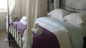 A bedroom with a four-poster bed, a wardrobe, and a patterned wallpaper. - Winton House (Stratford-upon-Avon)