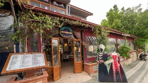 Un ristorante di cucina tradizionale ottomana con facciata in legno, fondamenta in mattoni e un'insegna con il menu all'esterno.