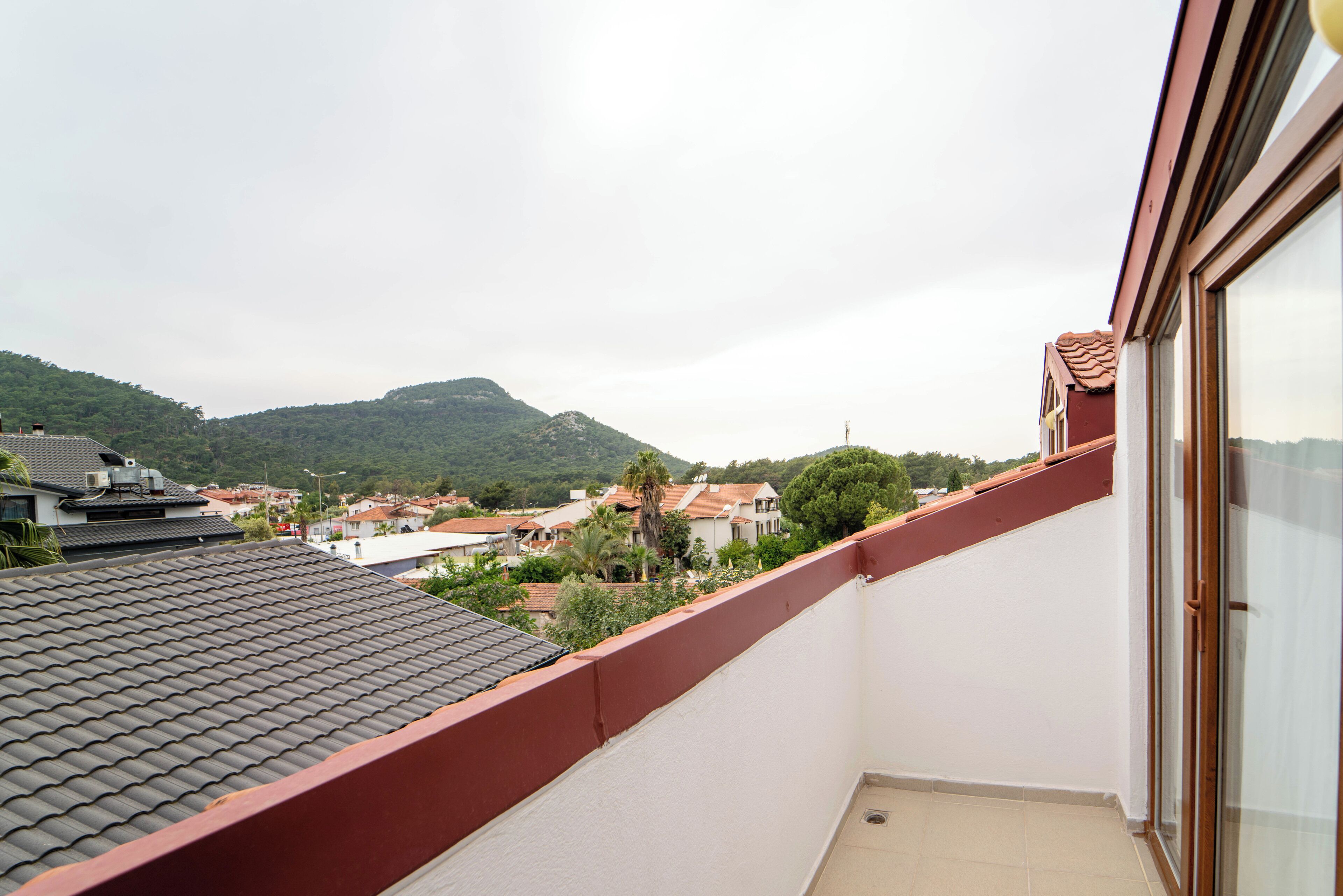 A balcony with a view of a hillside and buildings in the background.