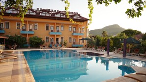 Un albergo con piscina, area salotto esterna e vista sulle montagne.