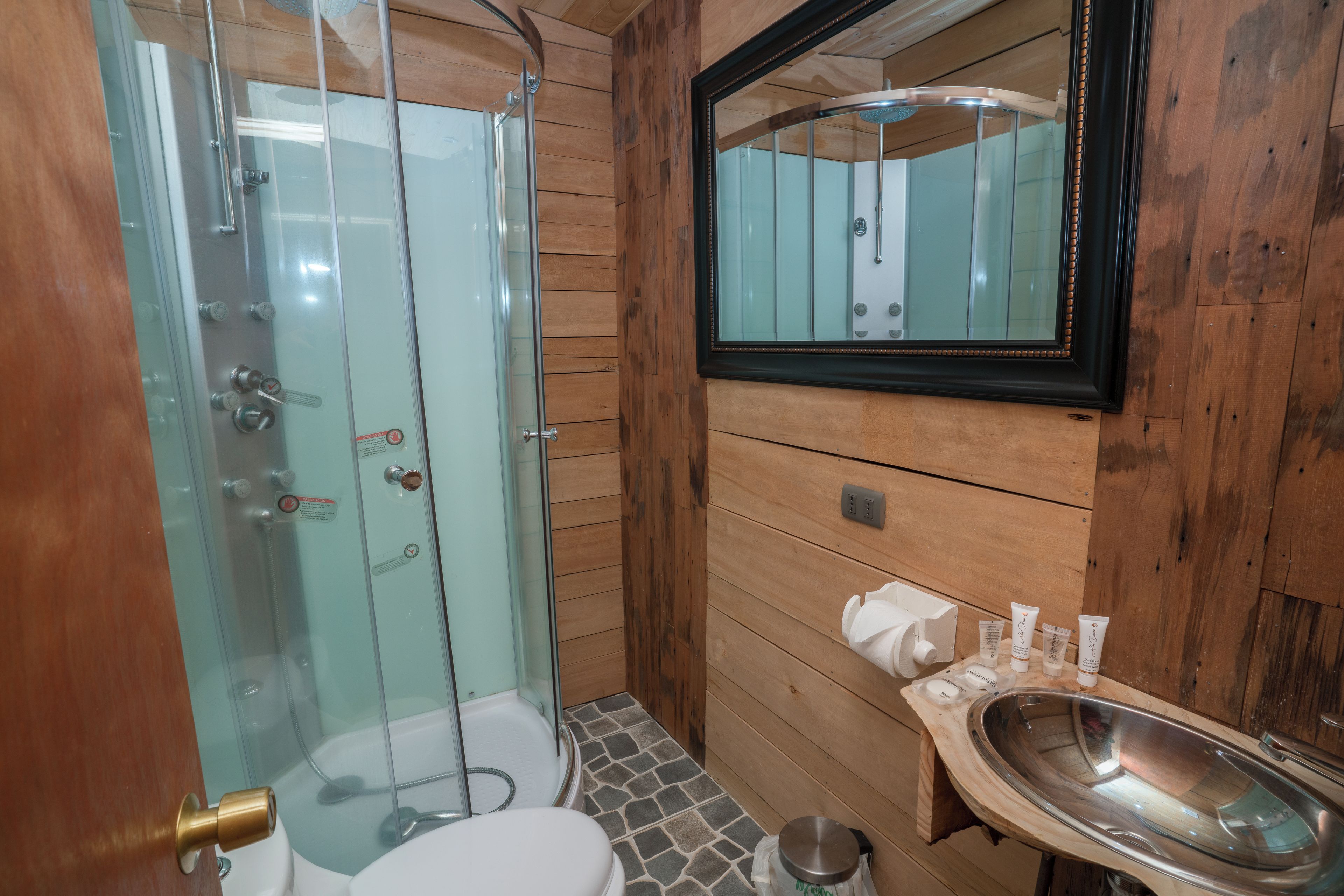 A bathroom with a glass-enclosed shower, a wooden vanity with a sink, and a mirror above the vanity.