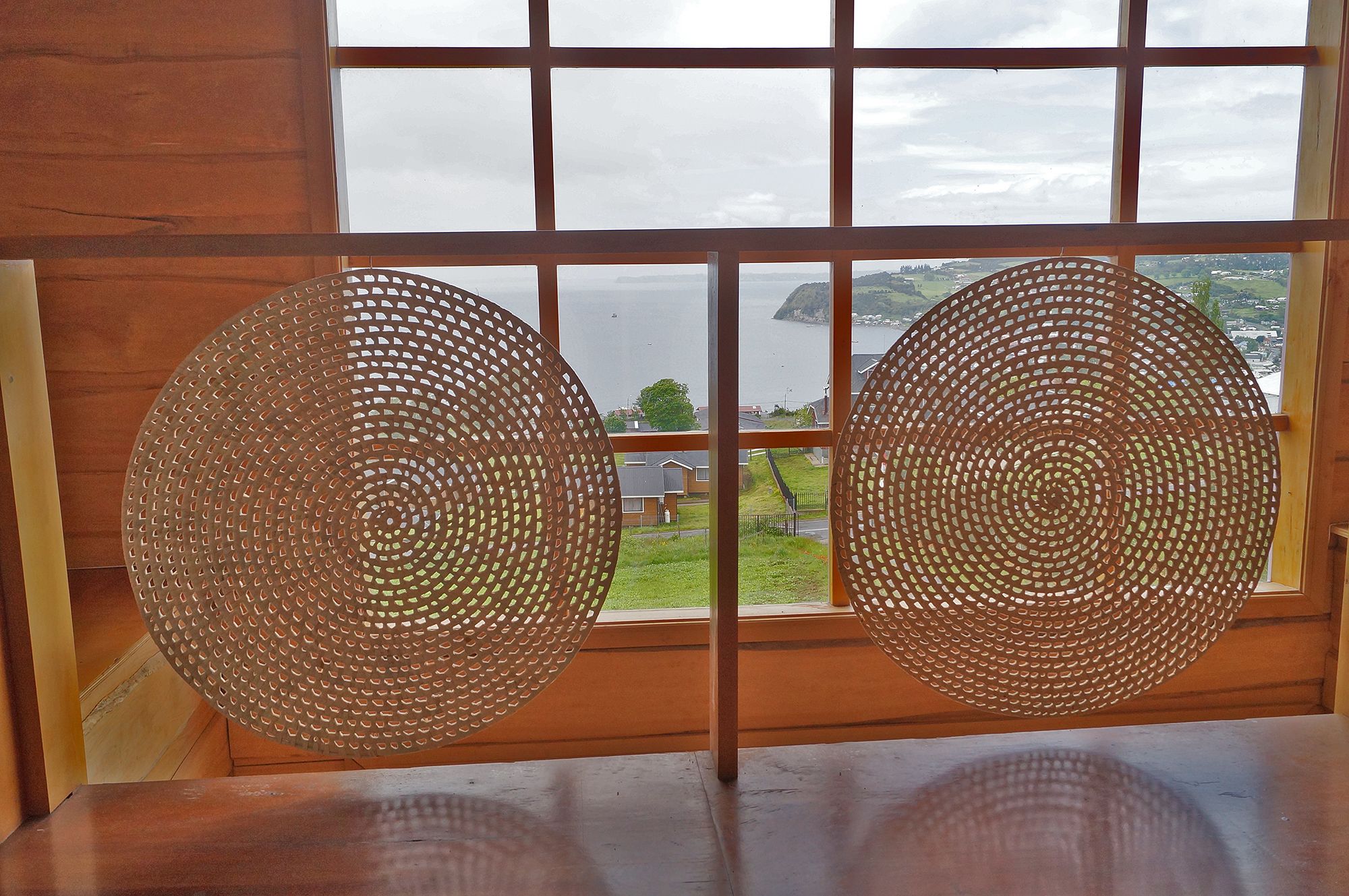 A room with a large window featuring a grid pattern and two circular metal decorations.