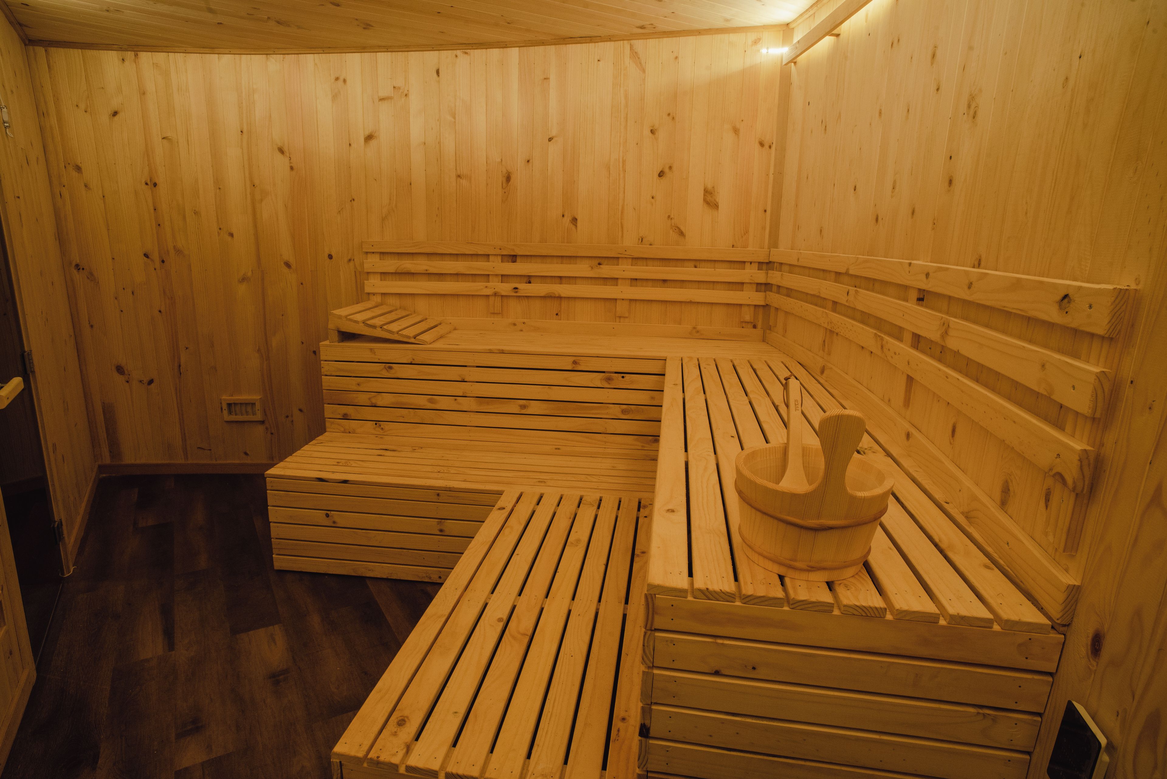 A sauna room with wooden benches and a wooden basin.